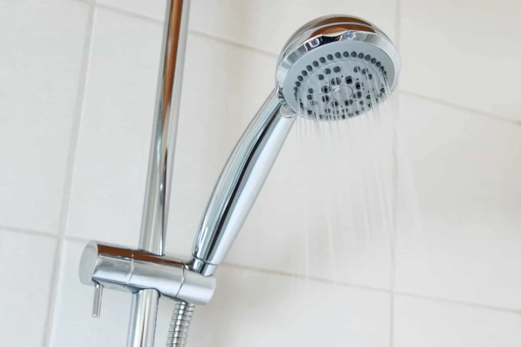 A shiny chrome shower head with multiple spray settings, attached to a tiled shower wall.