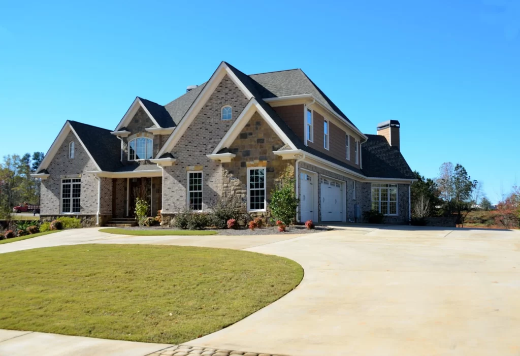 A lovely house with a neatly maintained landscape, including a lush green lawn and a paved driveway leading up to the front door.