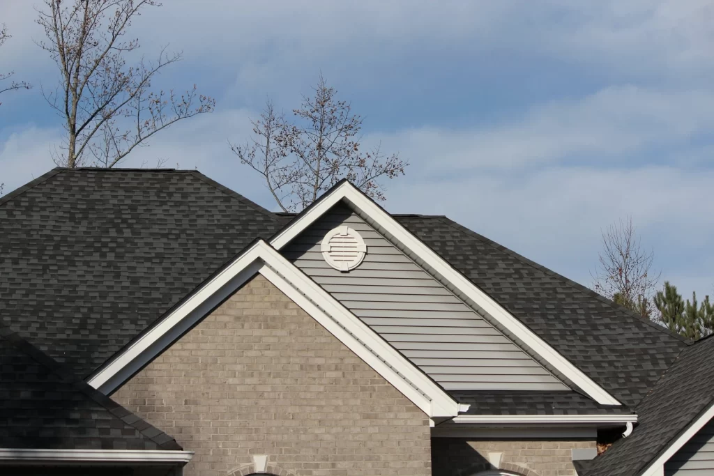 A view of the roof of a house, with asphalt shingles in shades of gray and brown covering the surface.